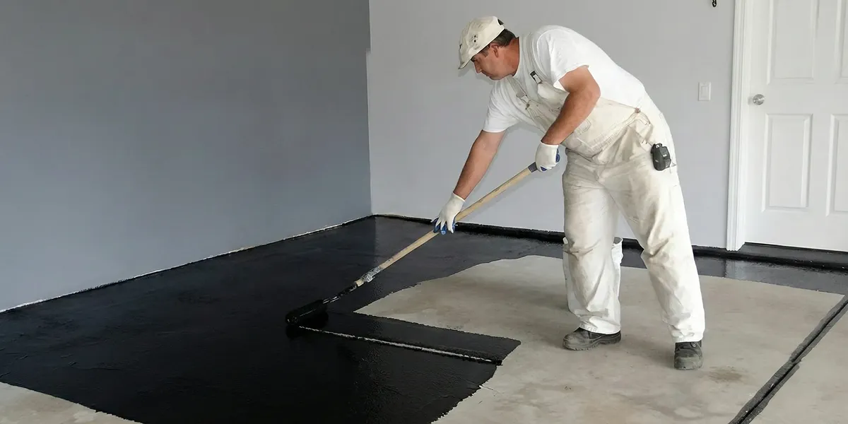 basement waterproofing professional applying waterproof coating to protect a basement floor in Peoria, IL